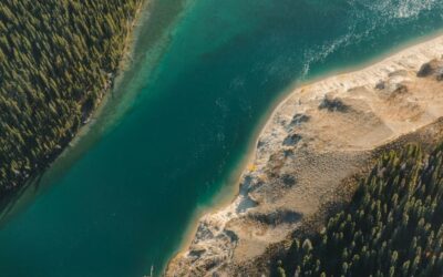 Luchtfoto van een diepblauw meer met beboste en zandige oevers